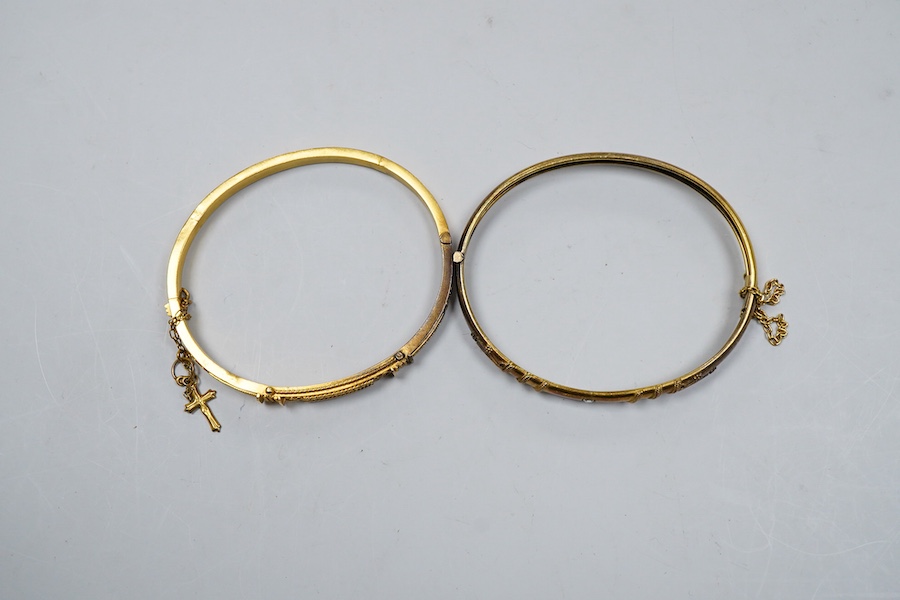 Two Victorian gold bangles, late 19th century, each of hinged design, with rope twist decoration, one later set with a carré-cut diamond, the other suspending a cross from a safety chain, inner circumferences approximate